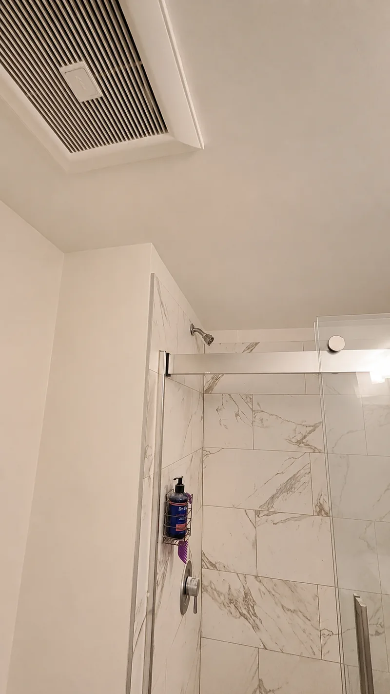 Finished drywall ceiling repair above a tiled shower