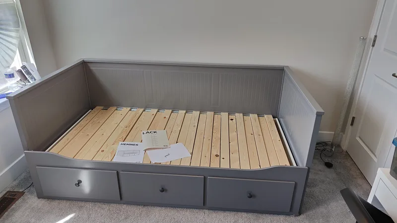 Gray daybed frame assembled with drawers and evenly spaced support slats