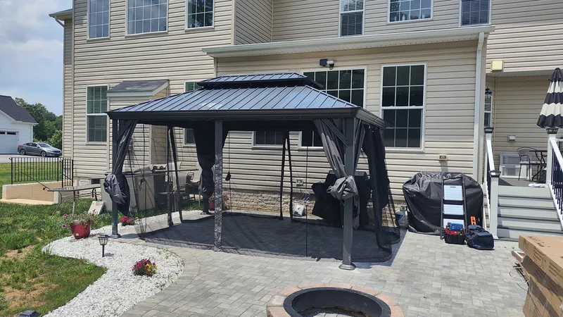 Large dark metal gazebo fully assembled on a backyard patio