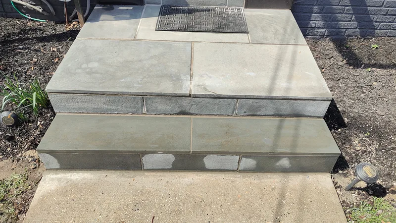 Repaired exterior stone entry steps with completed riser and edge